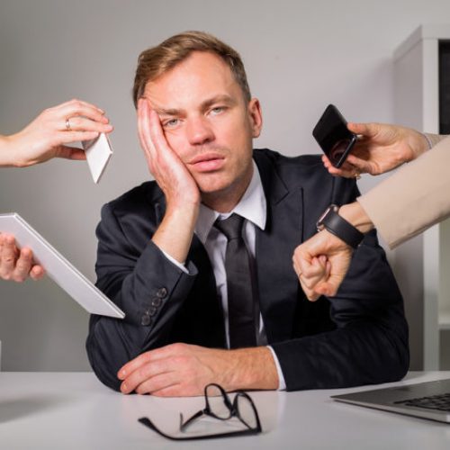 Tired man being overloaded at work with many tasks